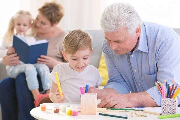 Lycklig senior man målning tillsammans med barnbarn hemma — Stockfoto