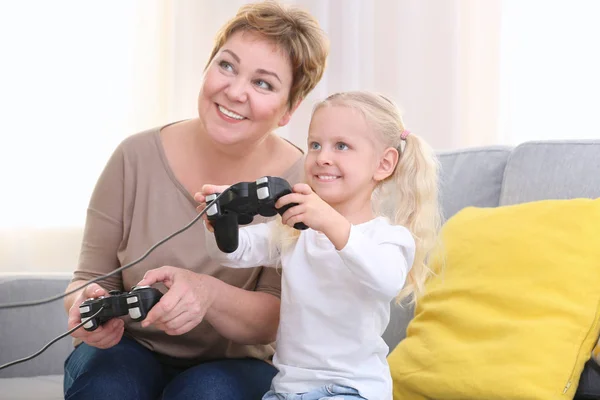 年长的妇女和她的孙女一起玩电子游戏在家 — 图库照片