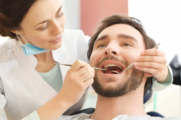 Dentist examining patient's teeth in clinic — Stock Photo, Image