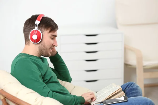 Concept de livre audio. Beau jeune homme avec écouteurs et livre — Photo