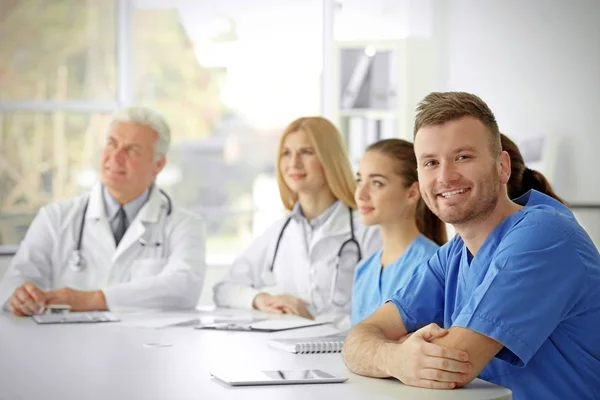 Equipe de médicos sentados à mesa na clínica — Fotografia de Stock