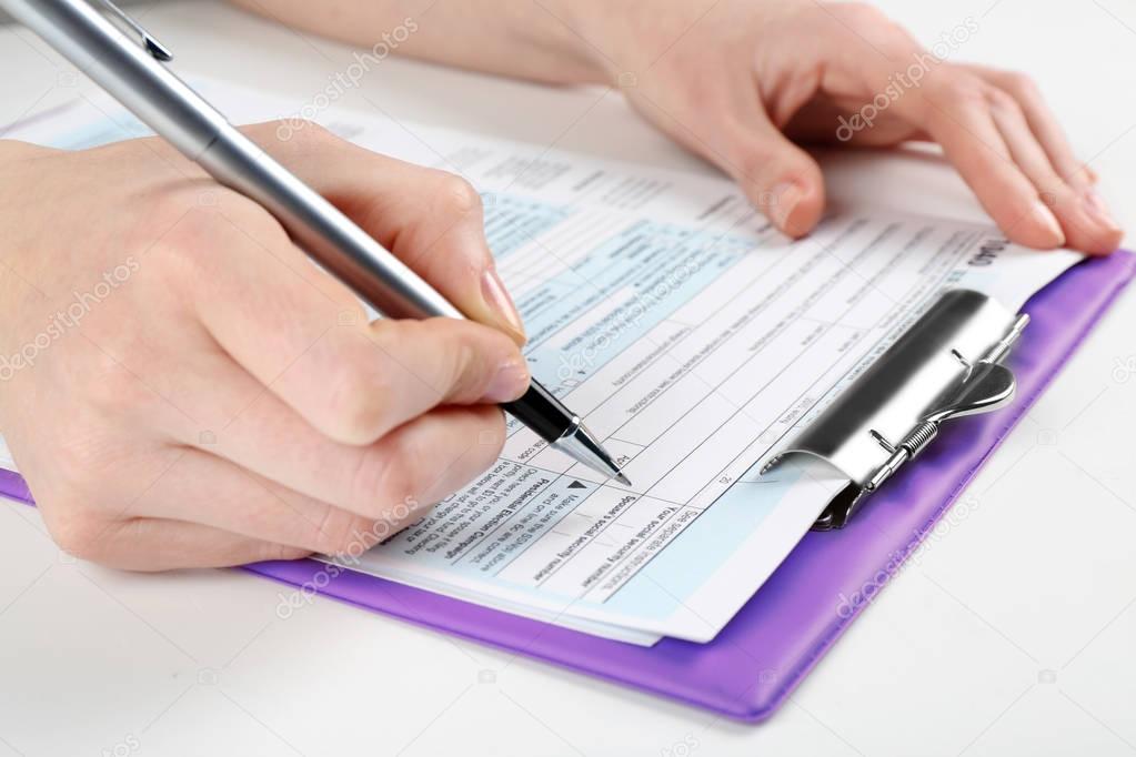 Woman filling form of Individual Income Tax Return, closeup