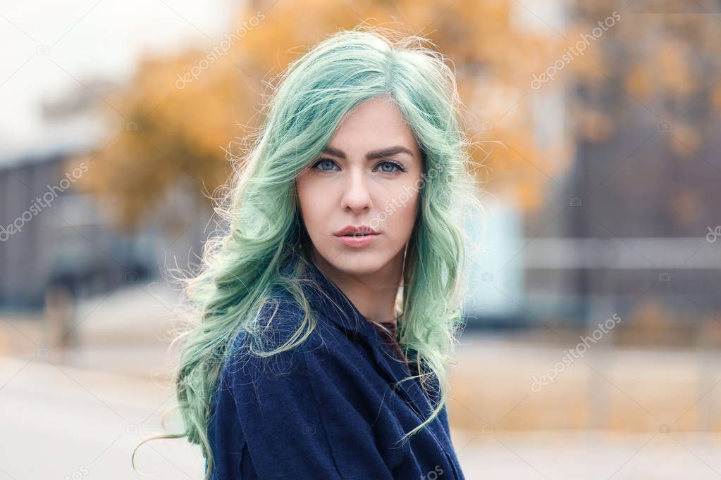 Trendy hairstyle ideas. Young woman with mint hair color on blurred background