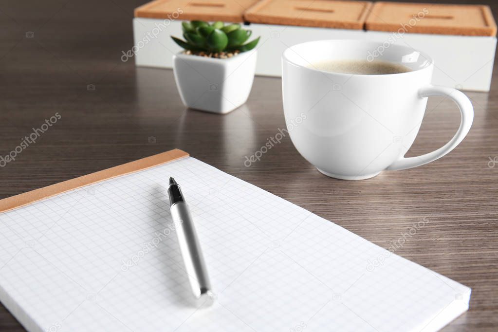 Empty notebook with pen and cup of coffee