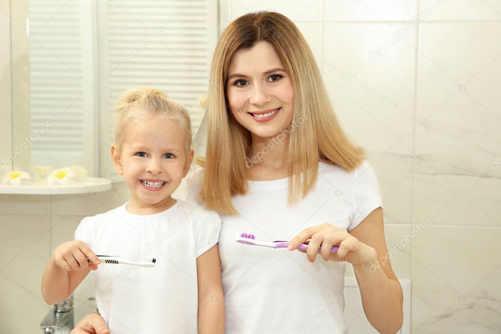 little girl with mother brushing teeth 