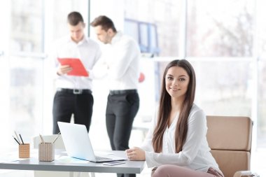 Ofis ve arka plan üzerinde bulanık insanlar çalışan güzel genç kadın