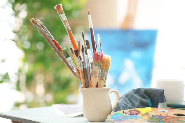 Cup with artist accessories — Stock Photo, Image