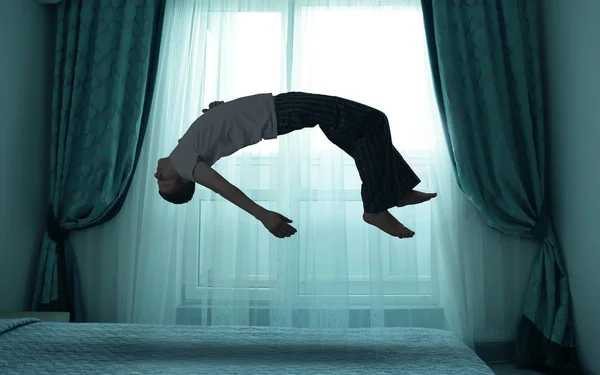 Sleep paralysis concept. Young man levitating over bed — Stock Photo, Image