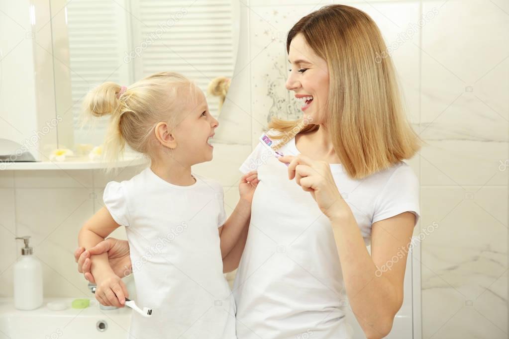 Little girl with mother brushing teeth