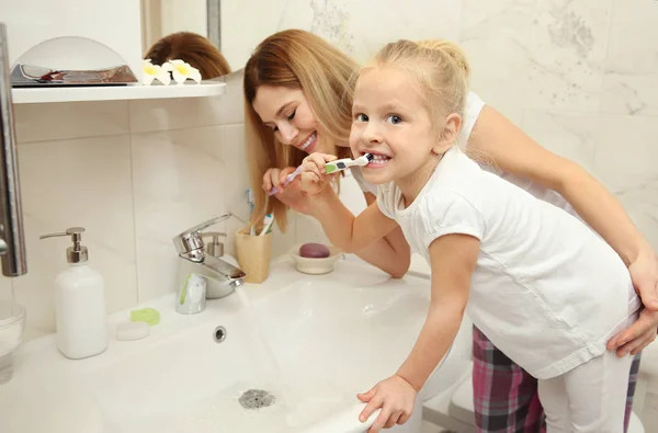Annesi diş fırçalama ile küçük kız — Stok fotoğraf