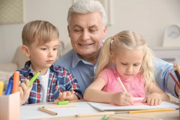 Gelukkig senior man schilderij samen met kleinkinderen thuis — Stockfoto