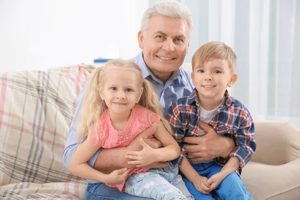 Glücklicher Senior und seine Enkel sitzen zu Hause auf dem Sofa — Stockfoto