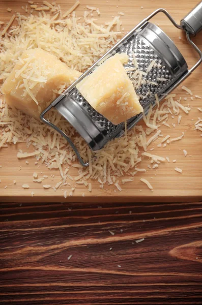 Cutting board with cheese and grater on wooden background — Stock Photo, Image