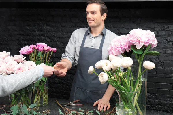 Florist receiving discount card from regular customer in flower shop