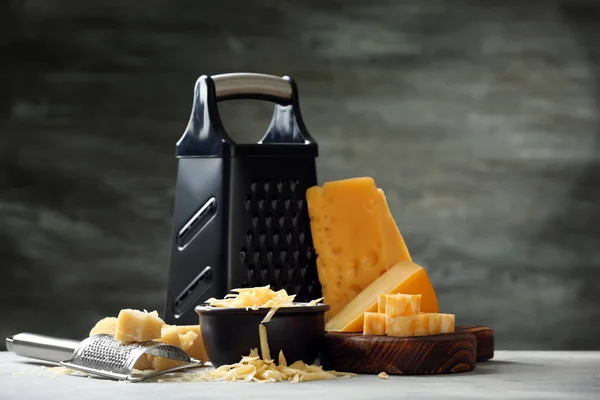 Tabla de cortar con queso, tazón y rejillas sobre fondo gris —  Fotos de Stock