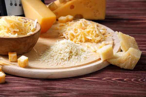 Bowl of cheese and cutting board on wooden background — Stock Photo, Image