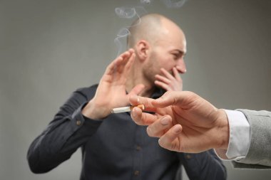 Genç adam gri arka plan üzerinde sigara reddediyor