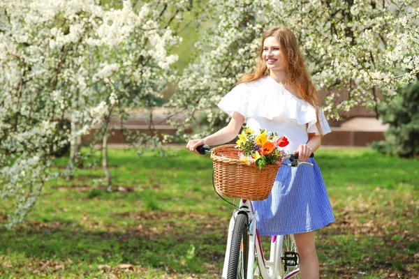 Pretty young girl with bicycle in park — Stock Photo, Image