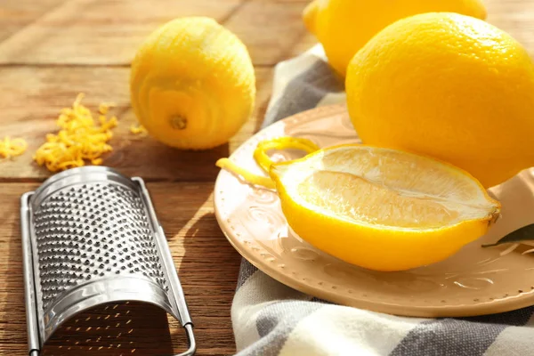 Лимоны и терка на деревянном столе — стоковое фото