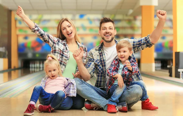 Familia feliz sentado en el suelo en el club de bolos —  Fotos de Stock