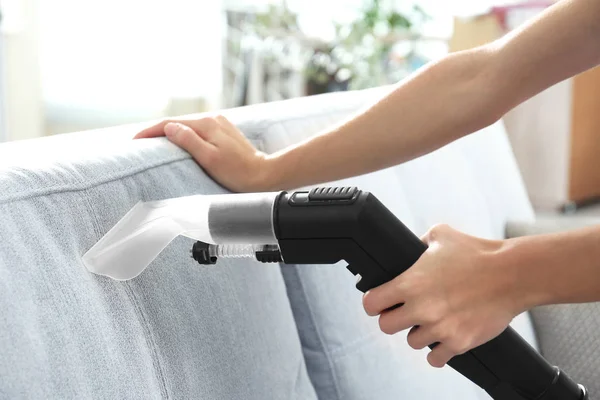 Female hands cleaning couch