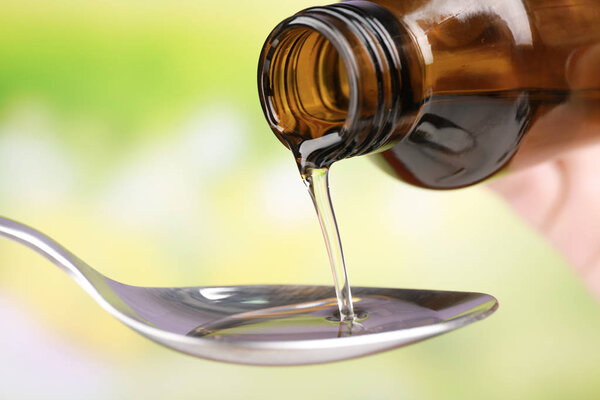 Pouring cough syrup into spoon  