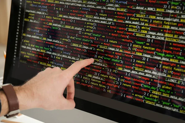 Mannenhand wijzend op computermonitor met programmacode, close-up — Stockfoto