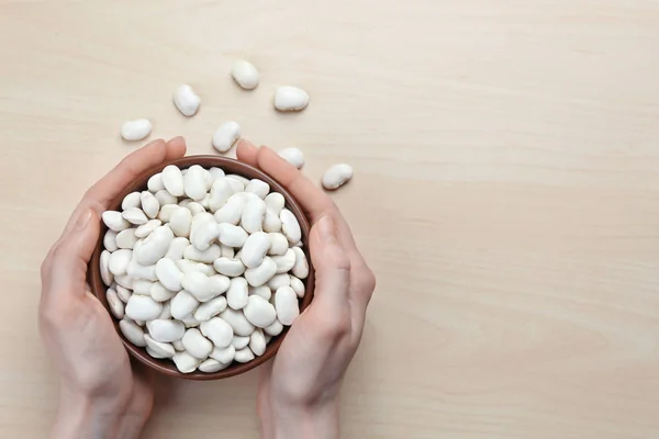 Manos sosteniendo tazón con frijoles mantequilla —  Fotos de Stock