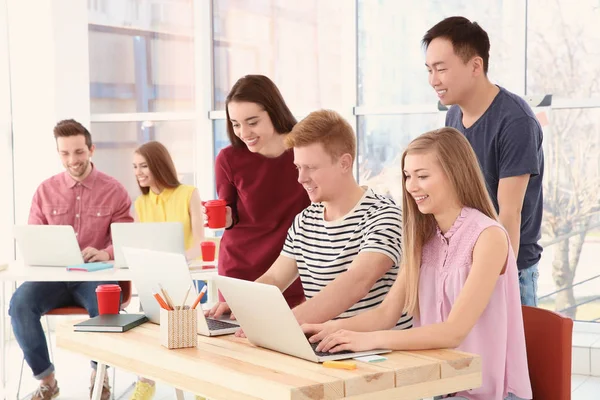 Jóvenes que trabajan con ordenadores portátiles en la oficina — Foto de Stock