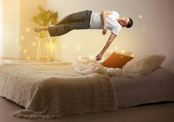 Концепция сонного паралича. Молодой человек левитирует над кроватью — стоковое фото