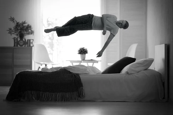 Conceito de paralisia do sono. Jovem levitando sobre a cama — Fotografia de Stock