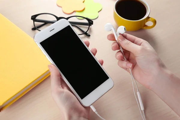 Vrouw met moderne telefoon en oortelefoons — Stockfoto