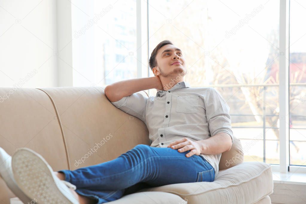 Happy young man resting on sofa