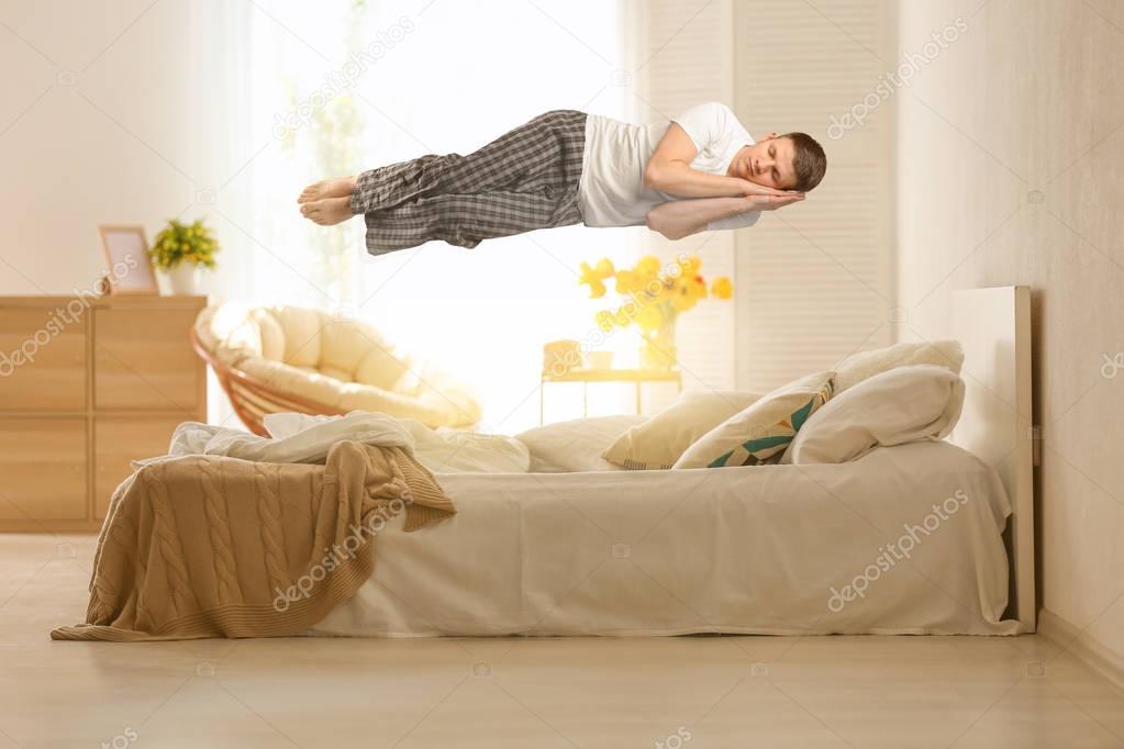 Sleep paralysis concept. Young man levitating over bed