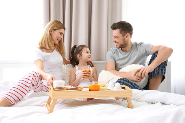 Rodzina siedzący na łóżko ze śniadaniem — Zdjęcie stockowe