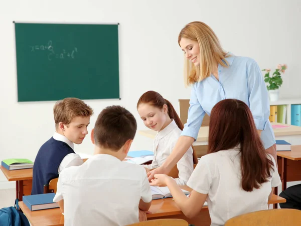 Kvinnlig lärare och elever gör uppgift i klassrummet — Stockfoto