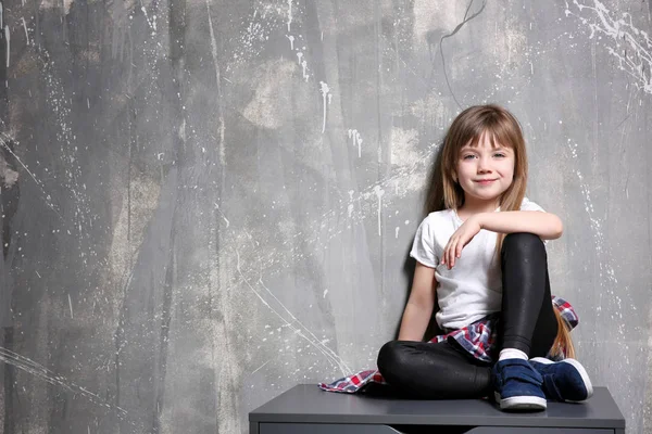 Girl sitting on chest of drawers — Stock Photo, Image