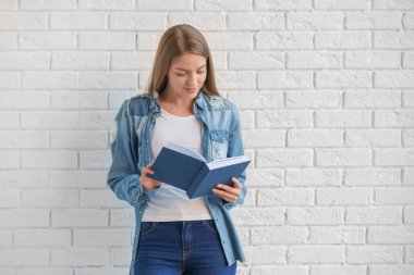 Kitap ayakta duvara yakın olan güzel kadın