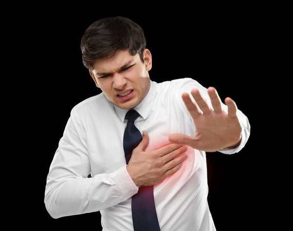 Heart attack concept. Man suffering from chest pain on black background