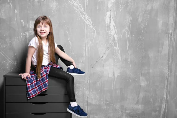 Menina sentada no peito das gavetas — Fotografia de Stock