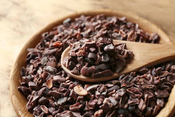 Wooden bowl and spoon with cocoa nibs — Stock Photo, Image