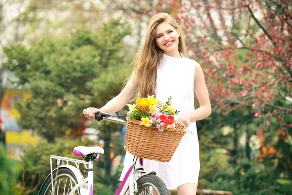 Mujer sonriente parada cerca de la bicicleta — Foto de Stock