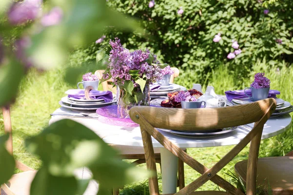 Tischdekoration mit fliederfarbenen Blumen — Stockfoto