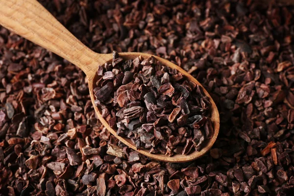 Heap of cocoa nibs and  spoon — Stock Photo, Image