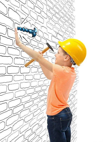 Маленький мальчик стучит вытянутым гвоздем винт в стену на белом фоне — стоковое фото