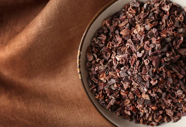 Bowl with cocoa nibs on cloth — Stock Photo, Image