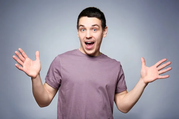 Guapo sorprendido joven sobre fondo gris — Foto de Stock