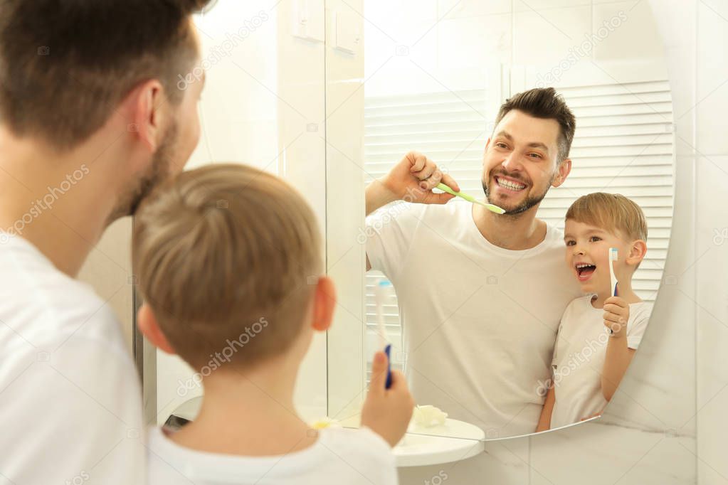 father with son brushing teeth 