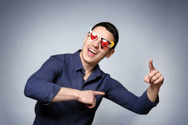 Šťastný mladý muž s brýlemi strany na šedém pozadí — Stock fotografie