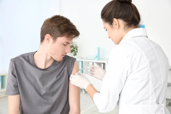 Mladý muž podáním injekce od Zdravotnický asistent v klinice — Stock fotografie